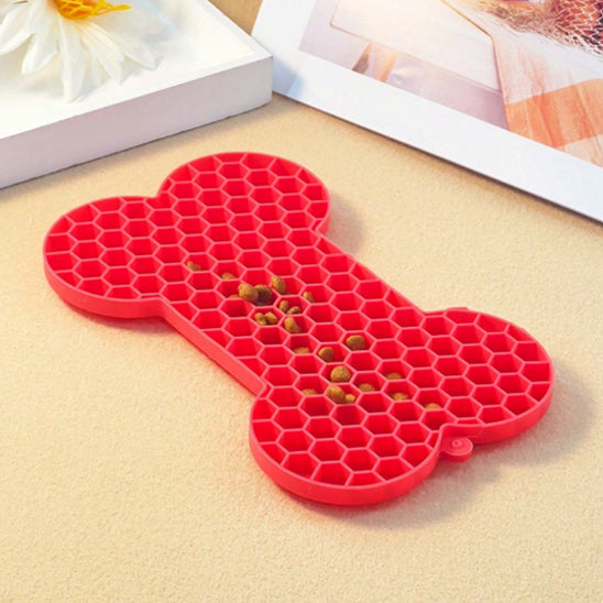 Tapis de léchage chien rouge en forme d’os avec croquettes posées dessus